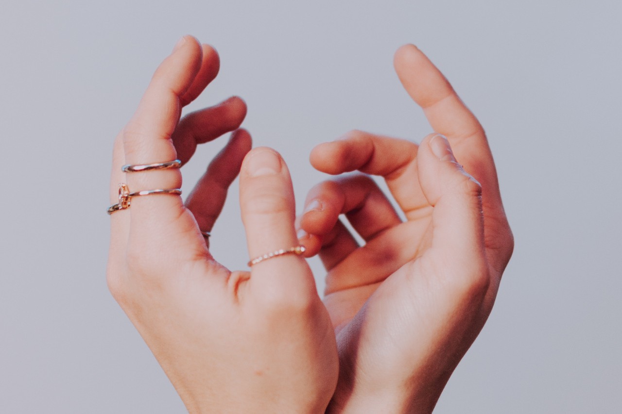 Two hands wearing multiple stackable bands