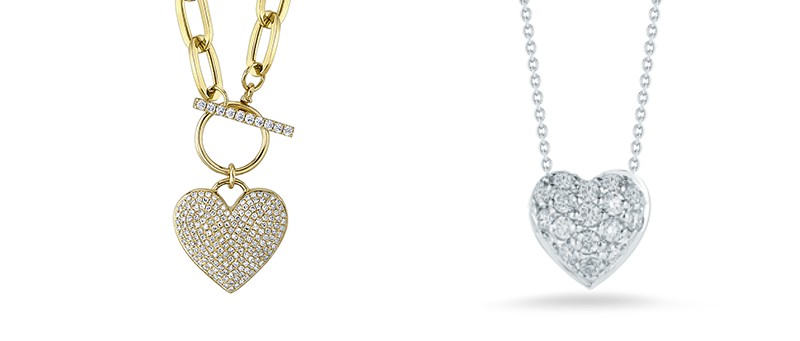 A gold and diamond studded heart pendant necklace next to a silver diamond studded pendant necklace
