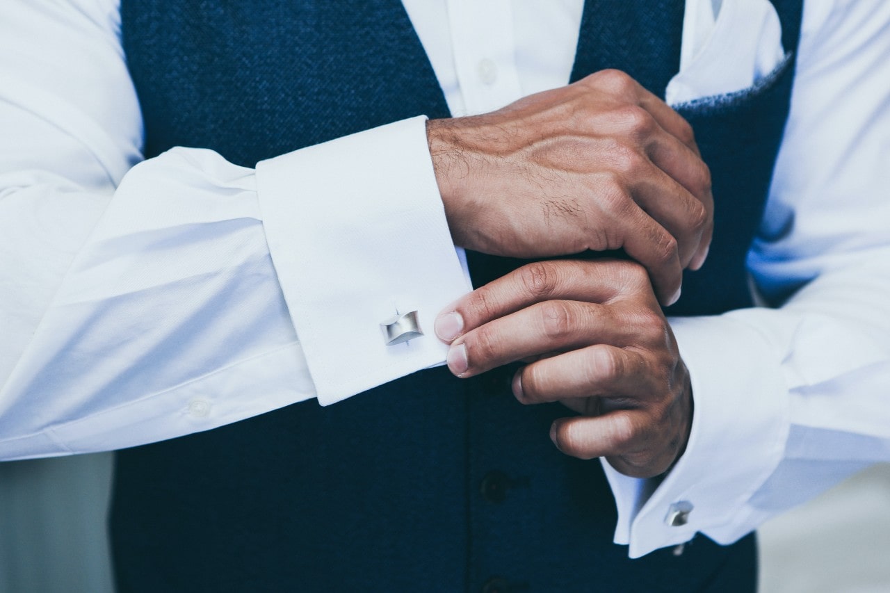 Close up of a man adjusting his shirt sleeve with a silver cufflink