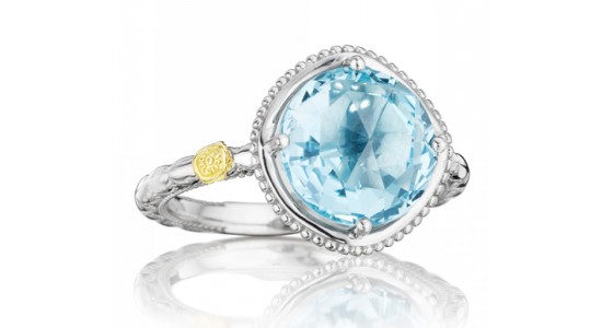 A silver fashion ring with a large blue topaz center stone and small yellow gold accent