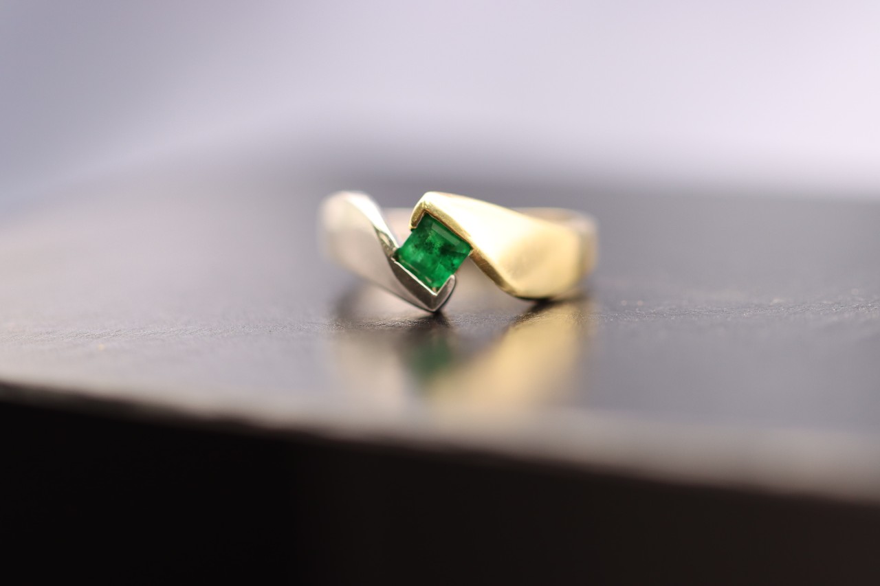 Green emerald engagement ring with a yellow gold setting