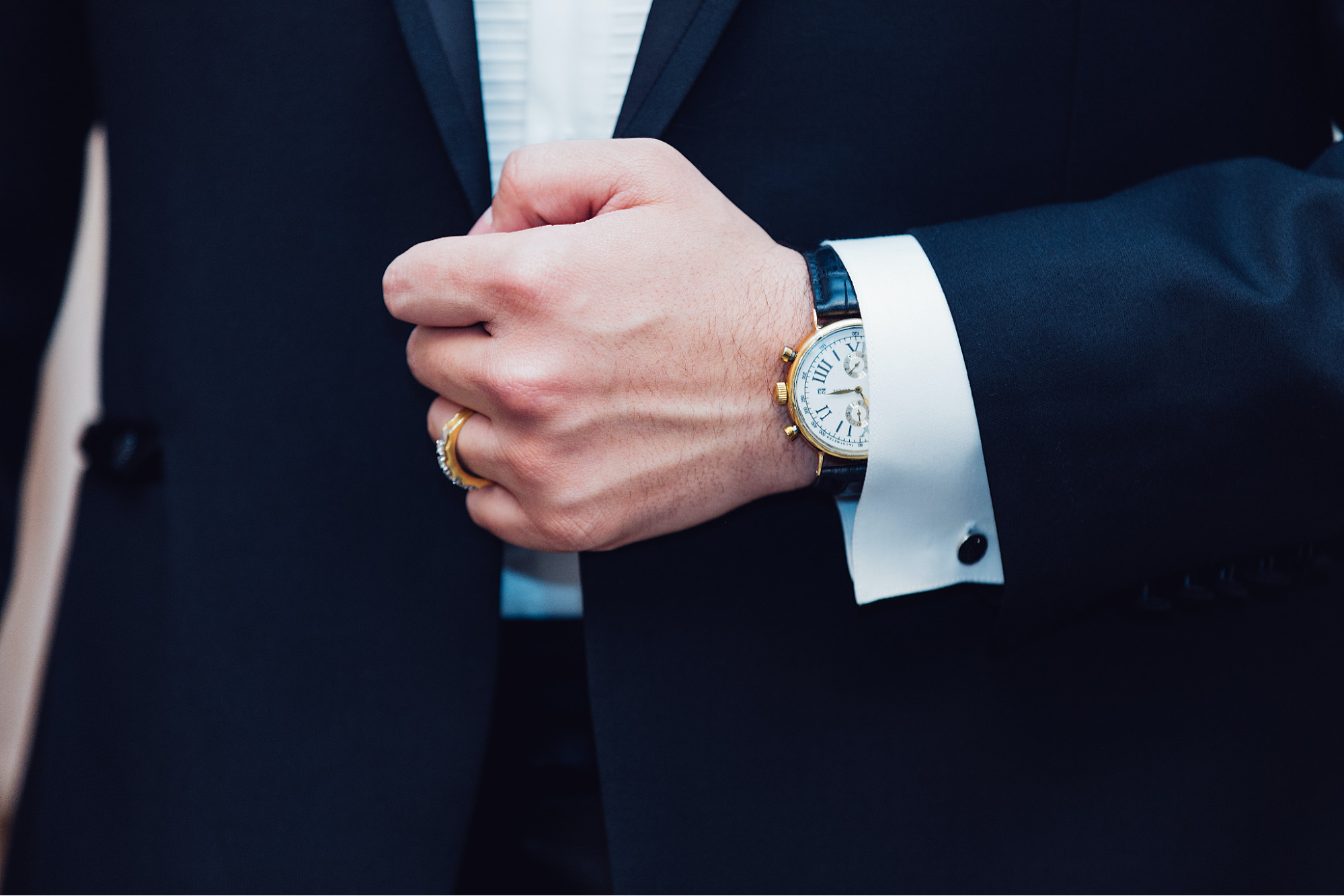 A man in a suit shows off his luxury dress watch