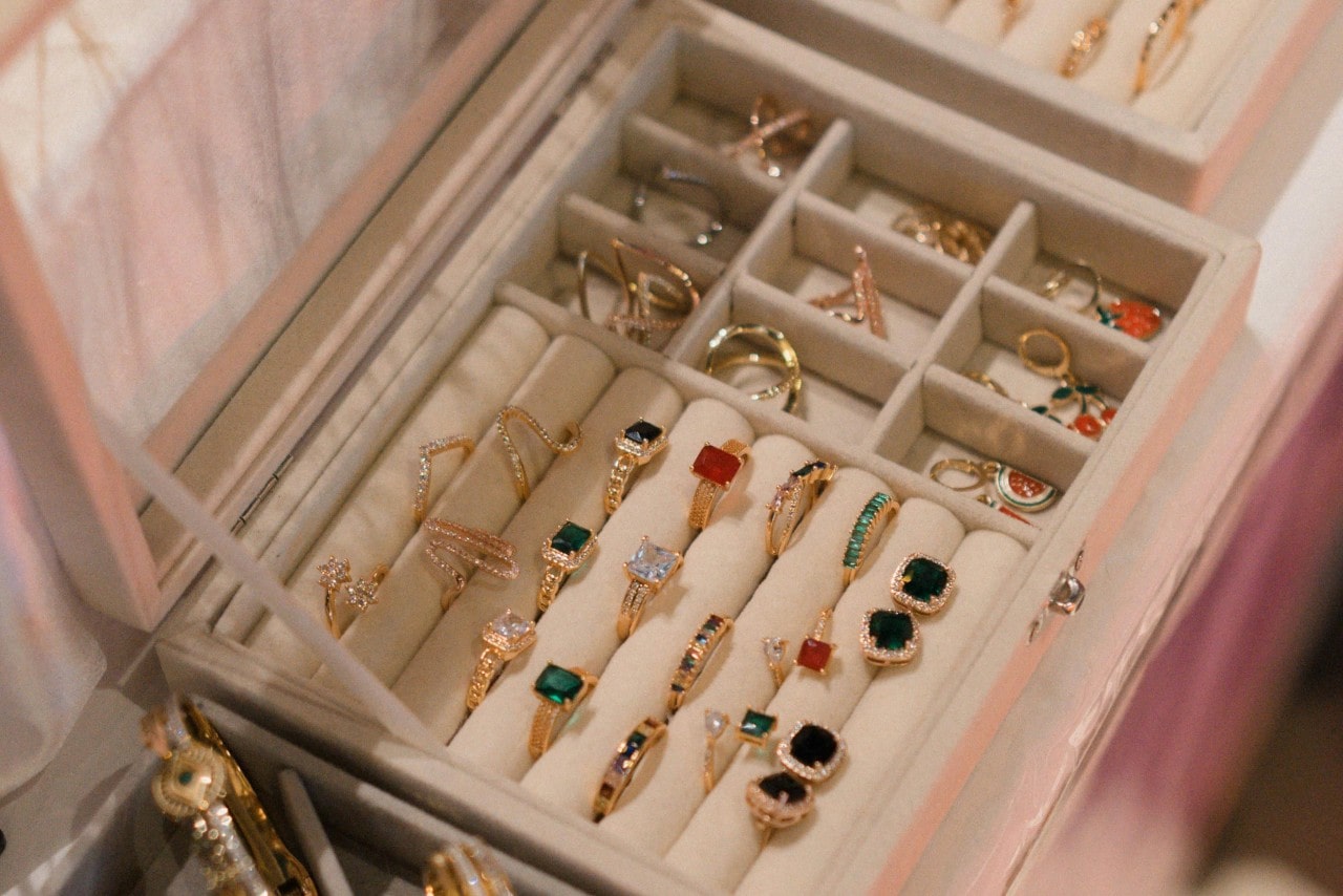A jewelry box filled with yellow gold rings adorned with colorful gemstones and intricate designs.