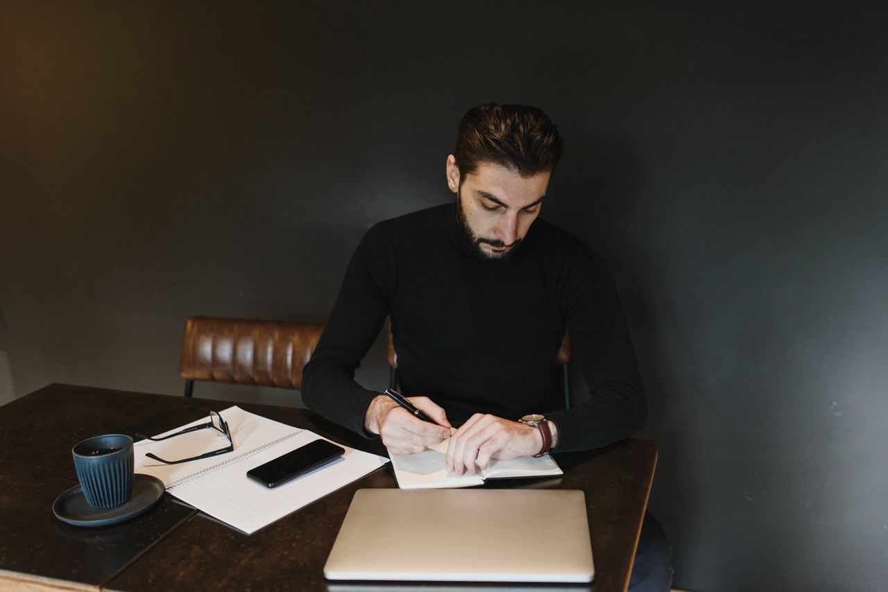 A college student studying looks at his watch.