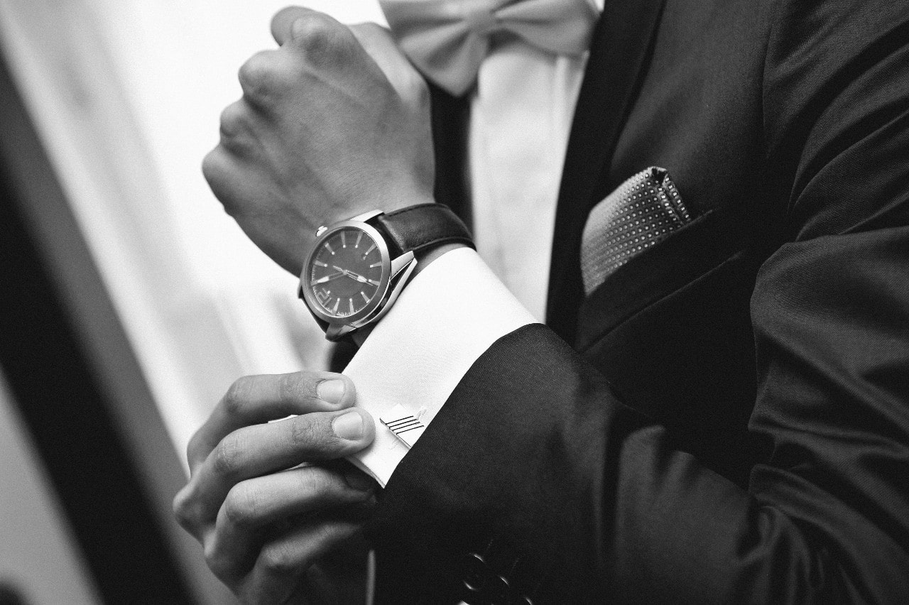 close-up of man’s wrist wearing a luxury watch and suit
