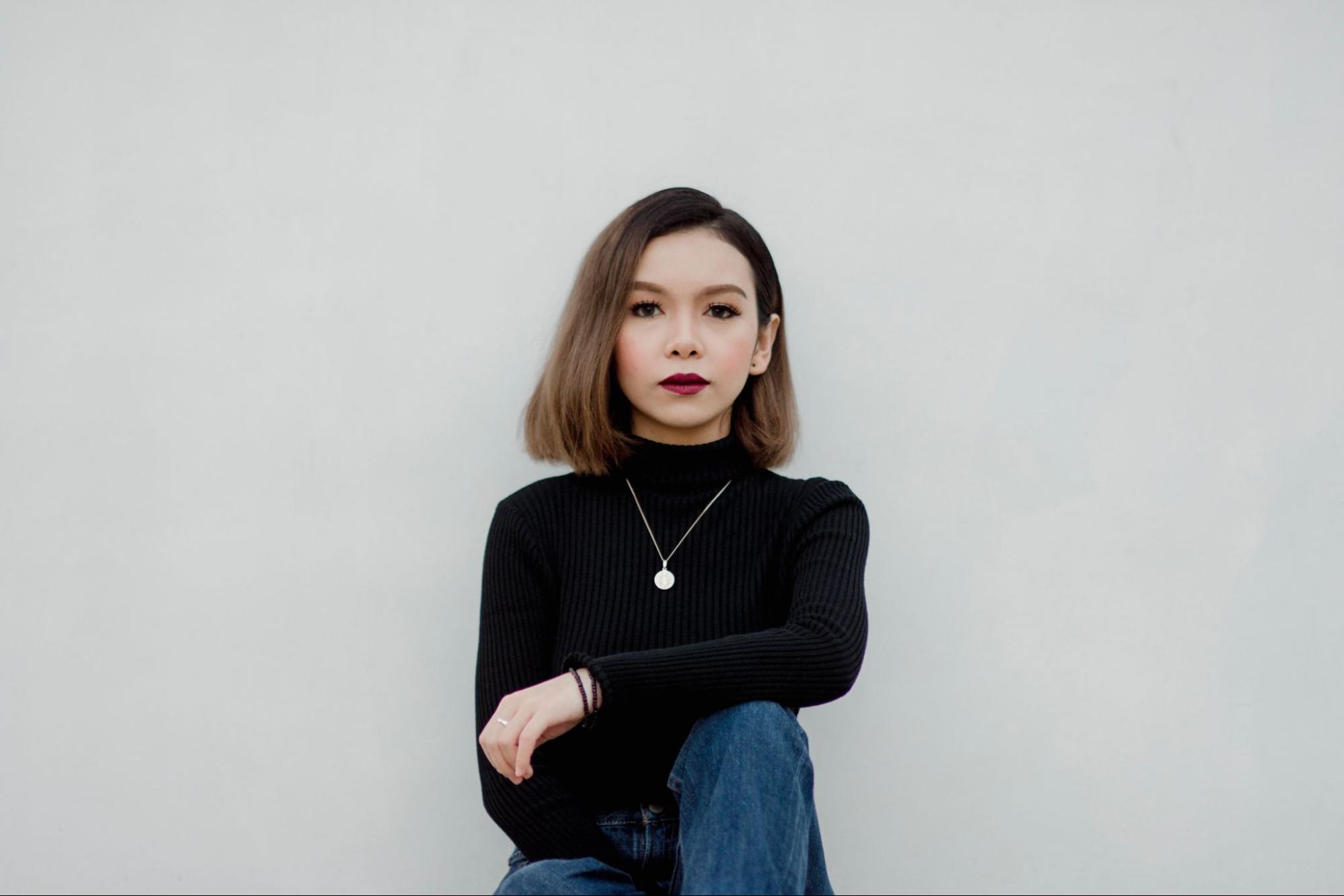 a woman in a black sweater wearing a silver circle necklace