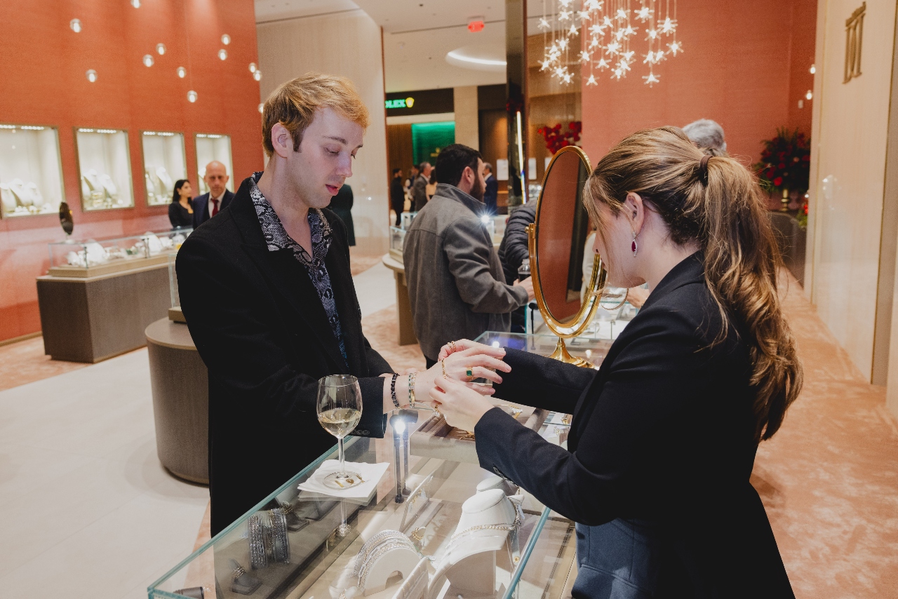 A jeweler assists a client with their bracelet across a jewelry display case in one of Deutsch & Deutsch’s showrooms.