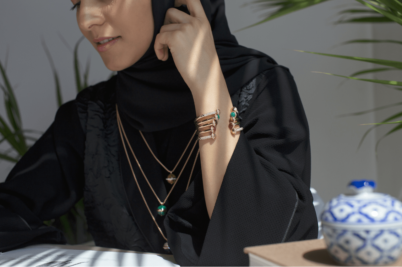 Woman in a black hijab clad in many necklaces and cuff bracelets.