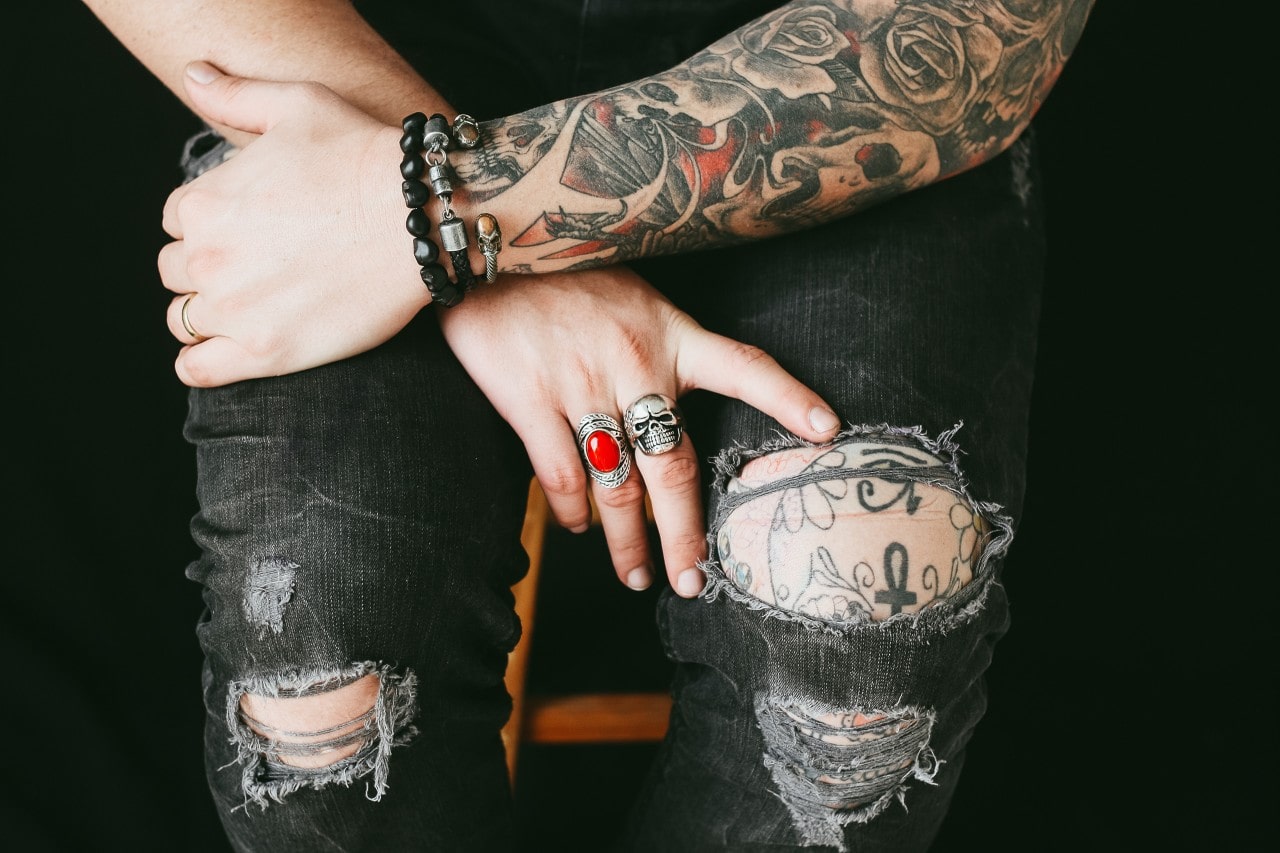 Punk person layering fashion rings and bracelets.