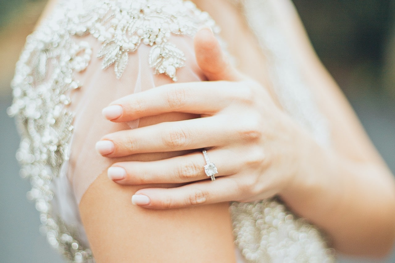 side stone engagement ring on a bride’s finger.