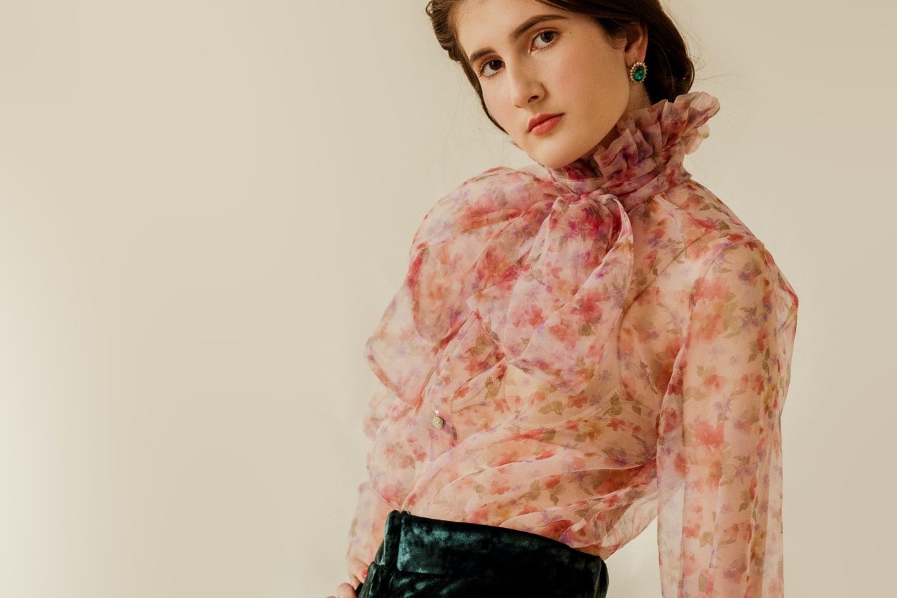 a woman in a floral top wearing a pair of vintage green gemstone earrings