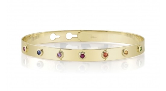 a yellow gold bangle bracelet featuring a variety of bezel set, multicolored gemstones