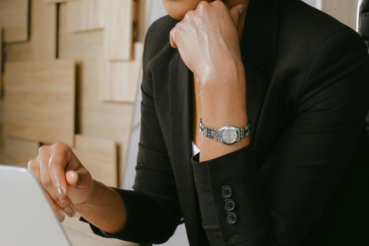 a woman working on a laptop and wearing a small sterling steel watch
