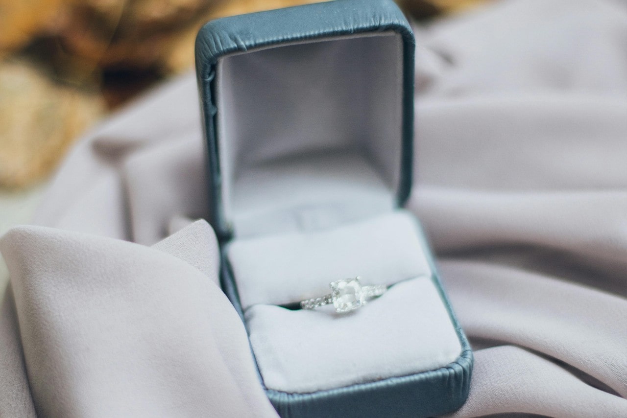 a princess cut diamond engagement ring in a light blue ring box