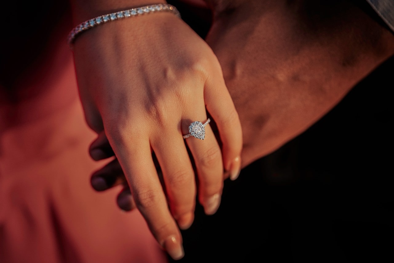A white gold diamond pear shaped engagement ring on a woman&rsquo;s hand