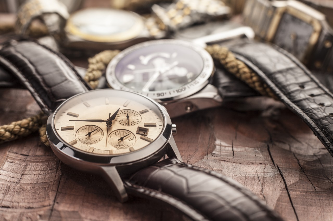 A close-up of luxury wristwatches with leather straps resting on a rustic wooden surface.