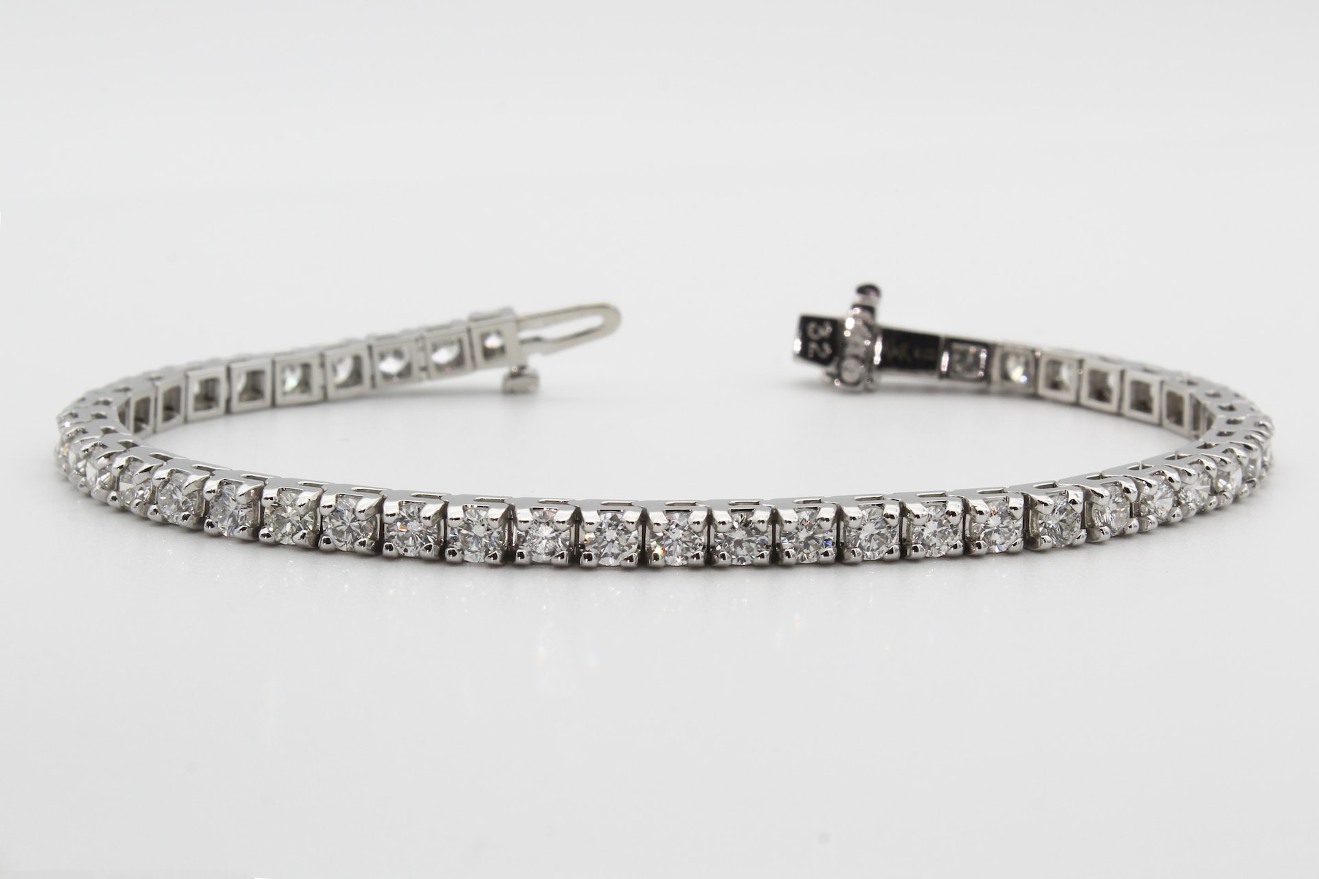 a white gold diamond tennis bracelet on a gray surface