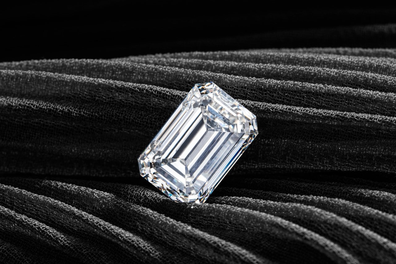 A close up of emerald cut diamond placed on a dark grey fabric