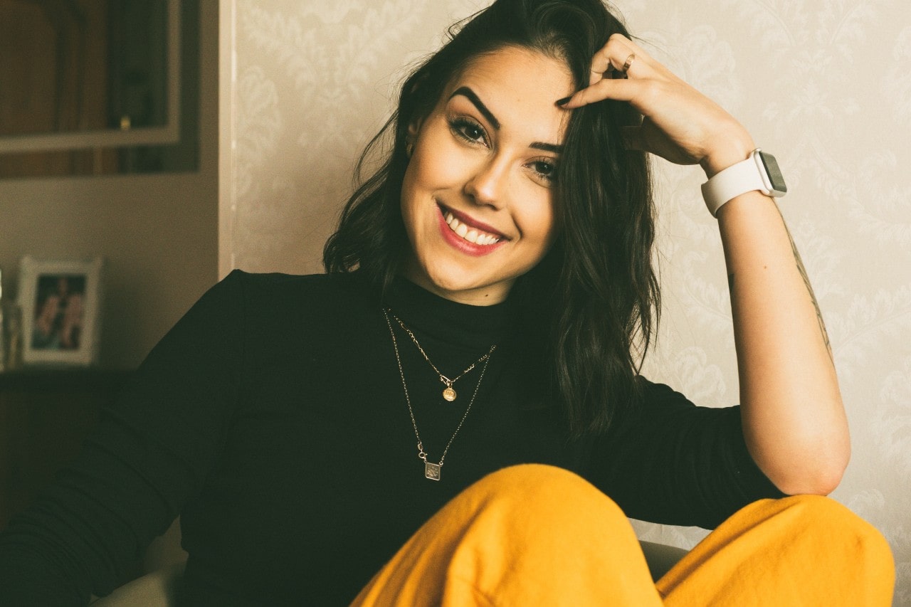 Woman smiling while wearing a coupe of pendant necklaces