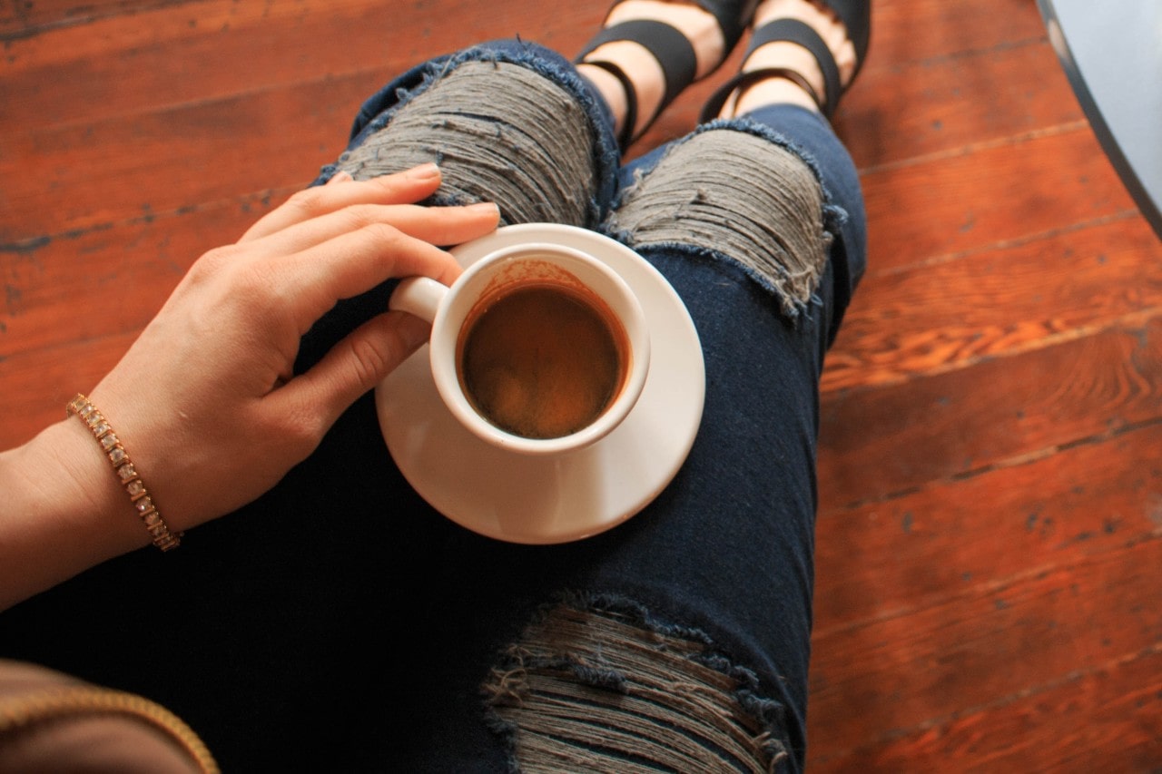 woman having coffee while wearing a diamond and yellow gold bracelet