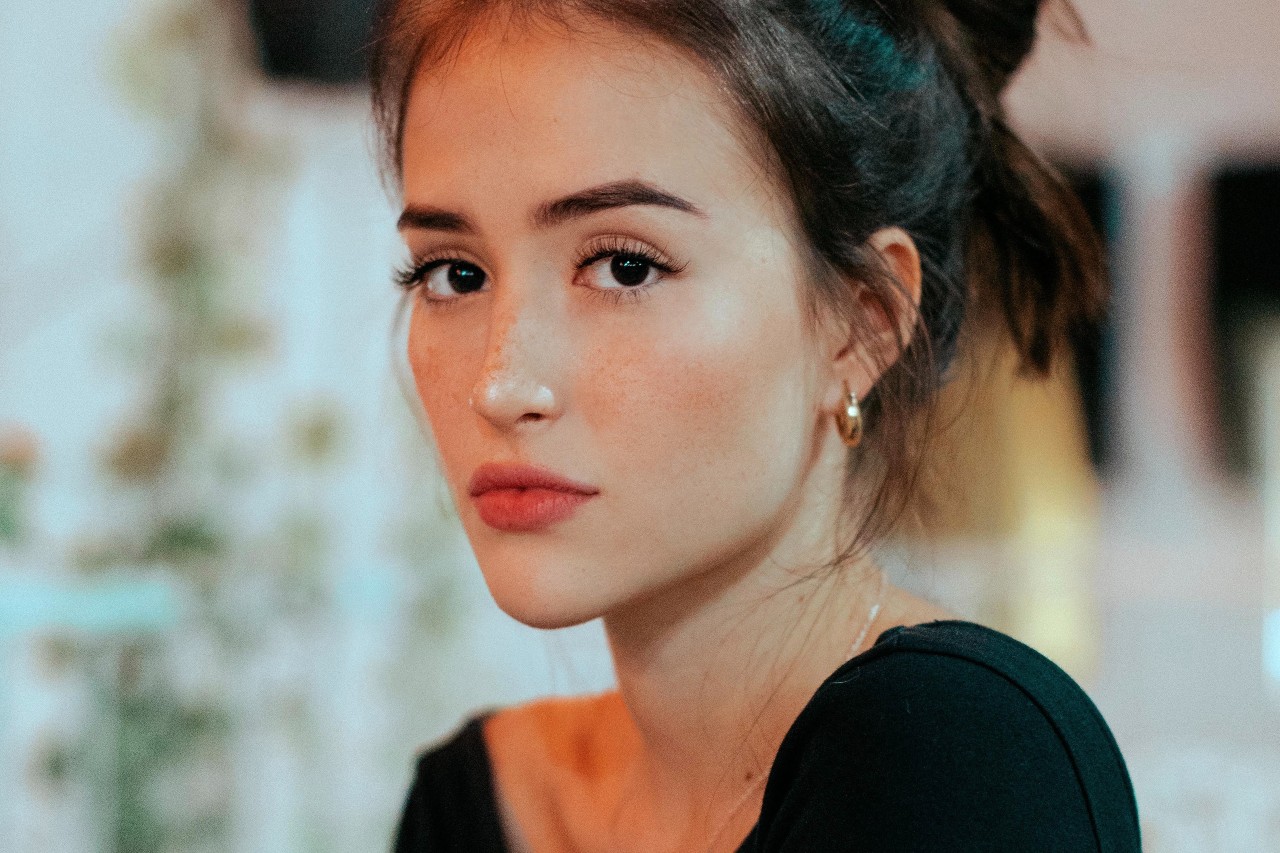 A woman in a store wears gold huggie earrings and a dainty chain necklace.