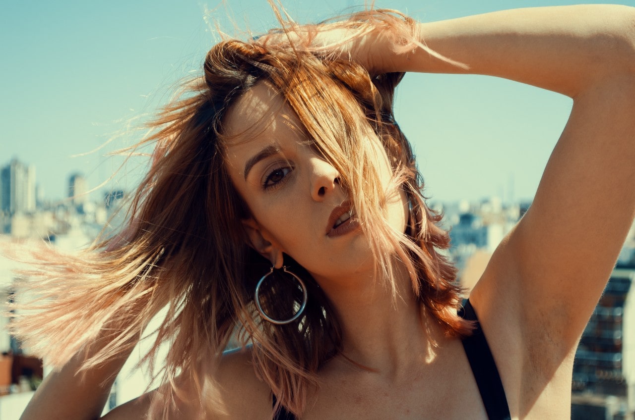 A woman on a windy day wears white gold hoop earrings.