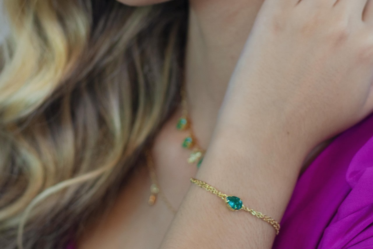 A close up image of a woman’s wrist adorned with a green gemstone bracelet. A close up image of a woman’s wrist adorned with a green gemstone bracelet.