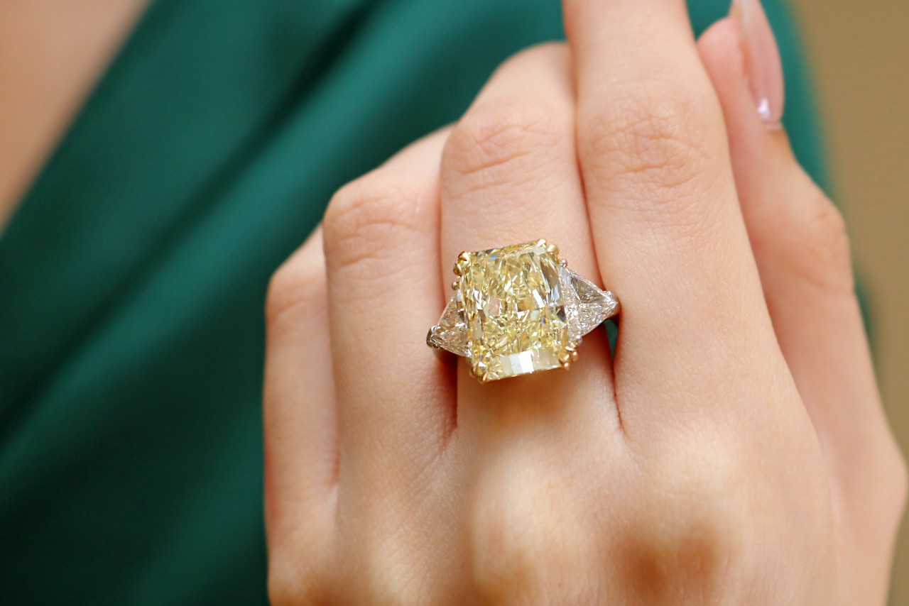 An impressive yellow diamond and clear diamond ring on the hand of a woman