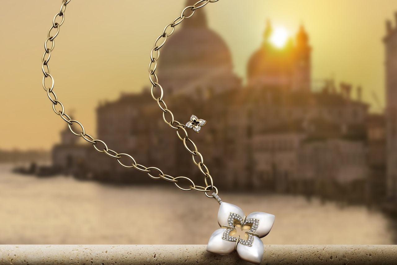 A signature floral pendant for Roberto Coin on elongated chain necklace with diamond charm detail.