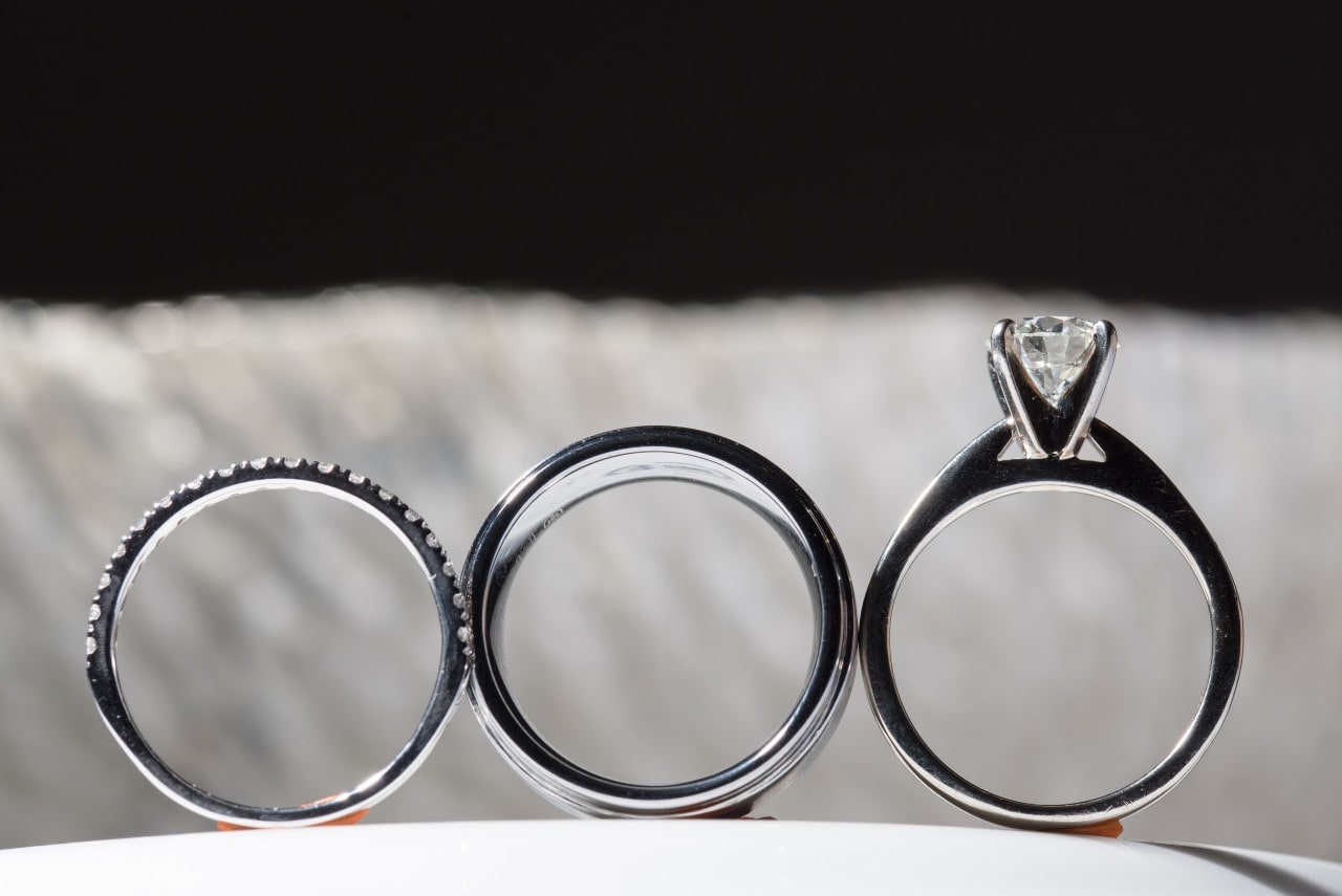 two wedding bands sit beside a solitaire engagement ring with a cathedral setting.
