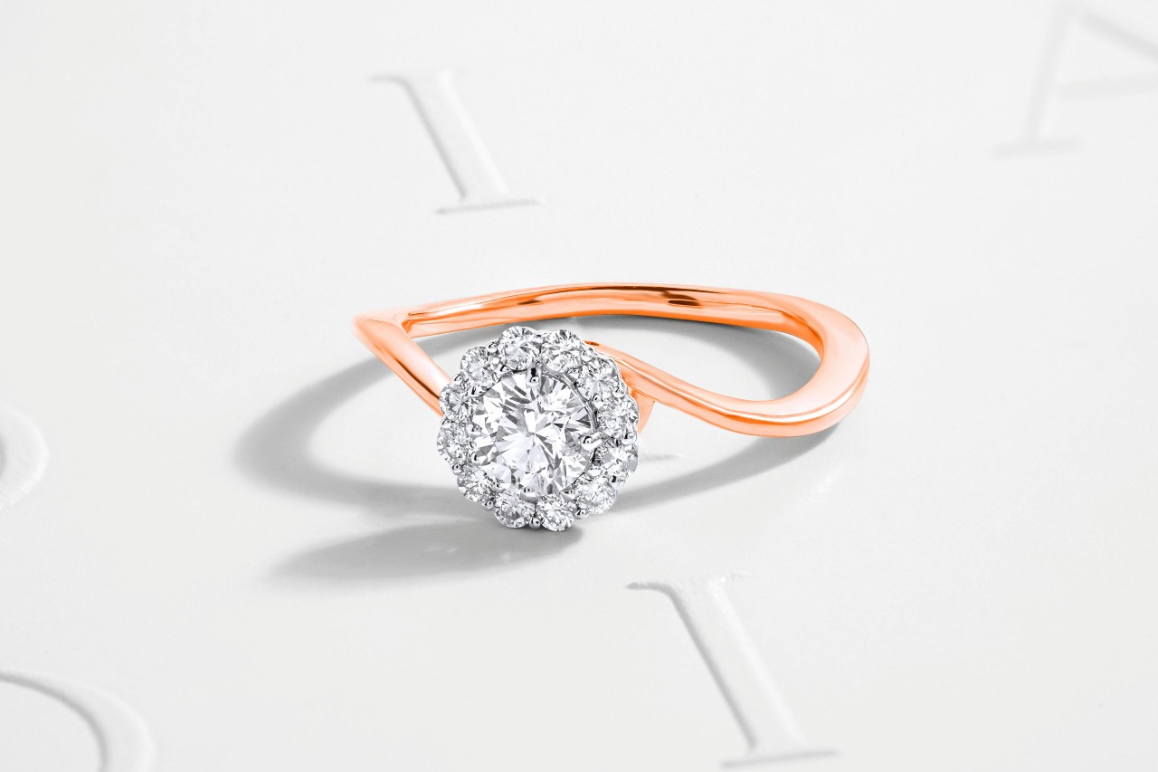 A mixed metal engagement ring with a curvy rose gold band and halo set stone. A mixed metal engagement ring with a curvy rose gold band and halo set stone.