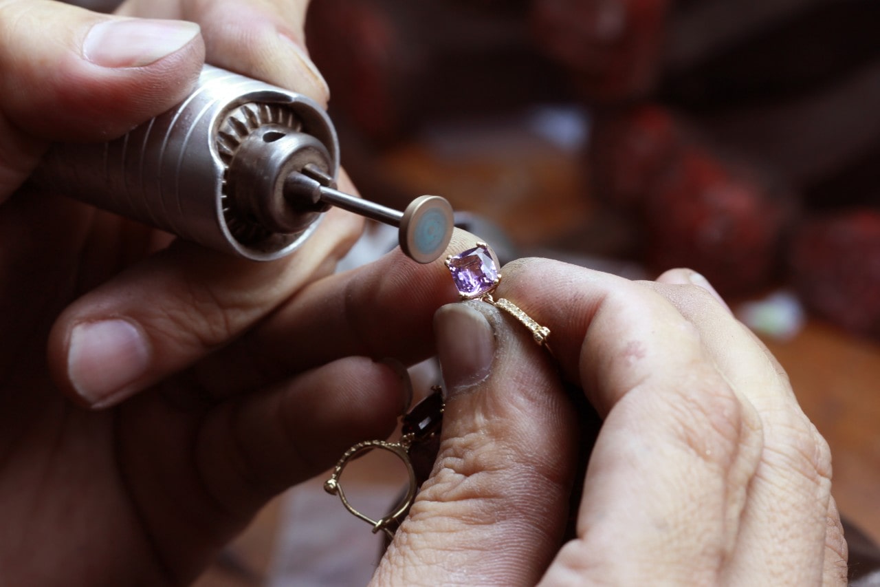a jeweler repairing a yellow gold earring with a power tool