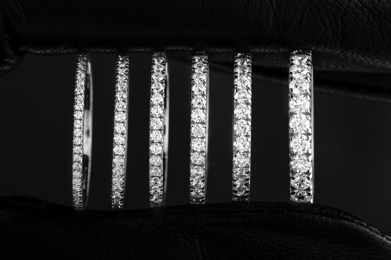 A row of diamond-studded white gold rings displayed against a black leather backdrop A row of diamond-studded white gold rings displayed against a black leather backdrop